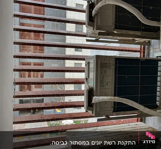 רשת מתוחה על חלון עם מזגנים חיצוניים